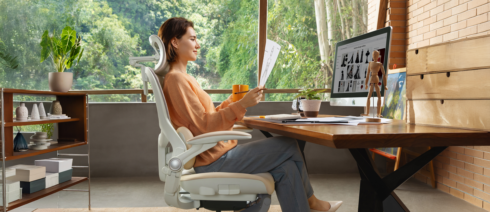 A woman sits upright in a CabeVibe S2 ergonomic chair, slightly reclined to 112 degrees, actively reading a document at her sunlit desk. This posture shows the ideal position for focused work and concentration.