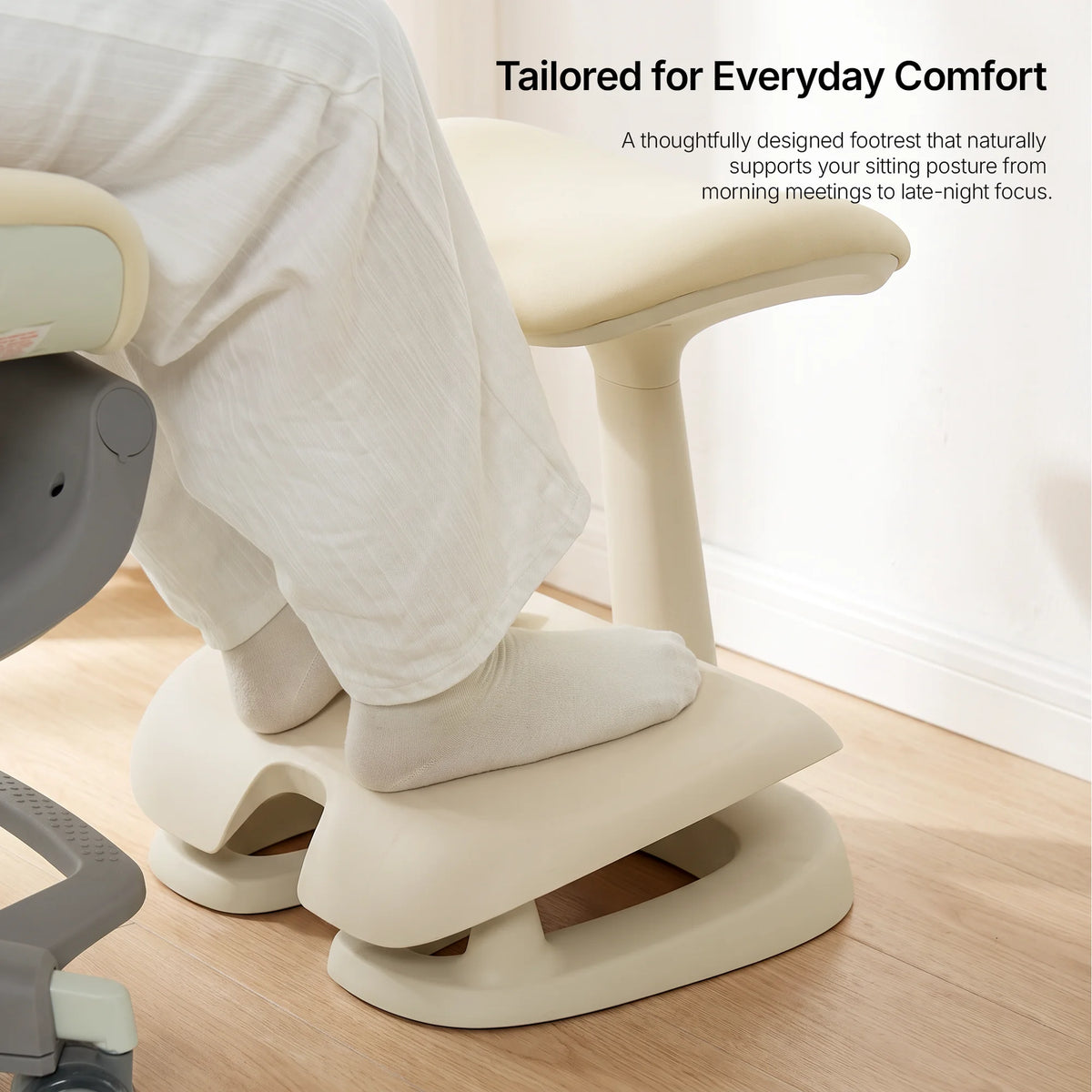 Close-up of legs resting on the cream Adjustable Under-Desk Footrest over a hardwood floor 